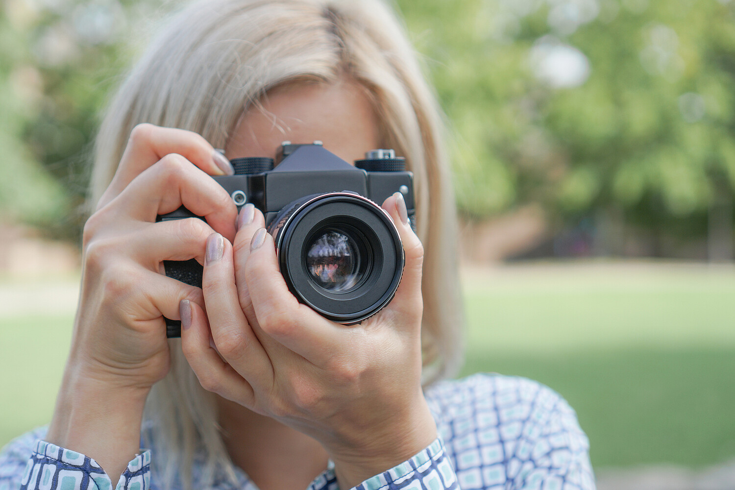 Girl blonde with a camera focuses in the park Girl blonde with a camera focuses in the park